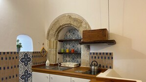 Una cucina con arco in pietra, zoccolo di piastrelle, piano di lavoro in legno e pensili.