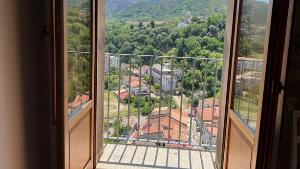 A view from a window overlooking a town with buildings and greenery. - Three Bedroom Apartment (TROPEA)