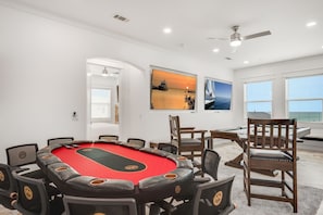 A room with a pool table, multiple chairs, and artwork on the walls.