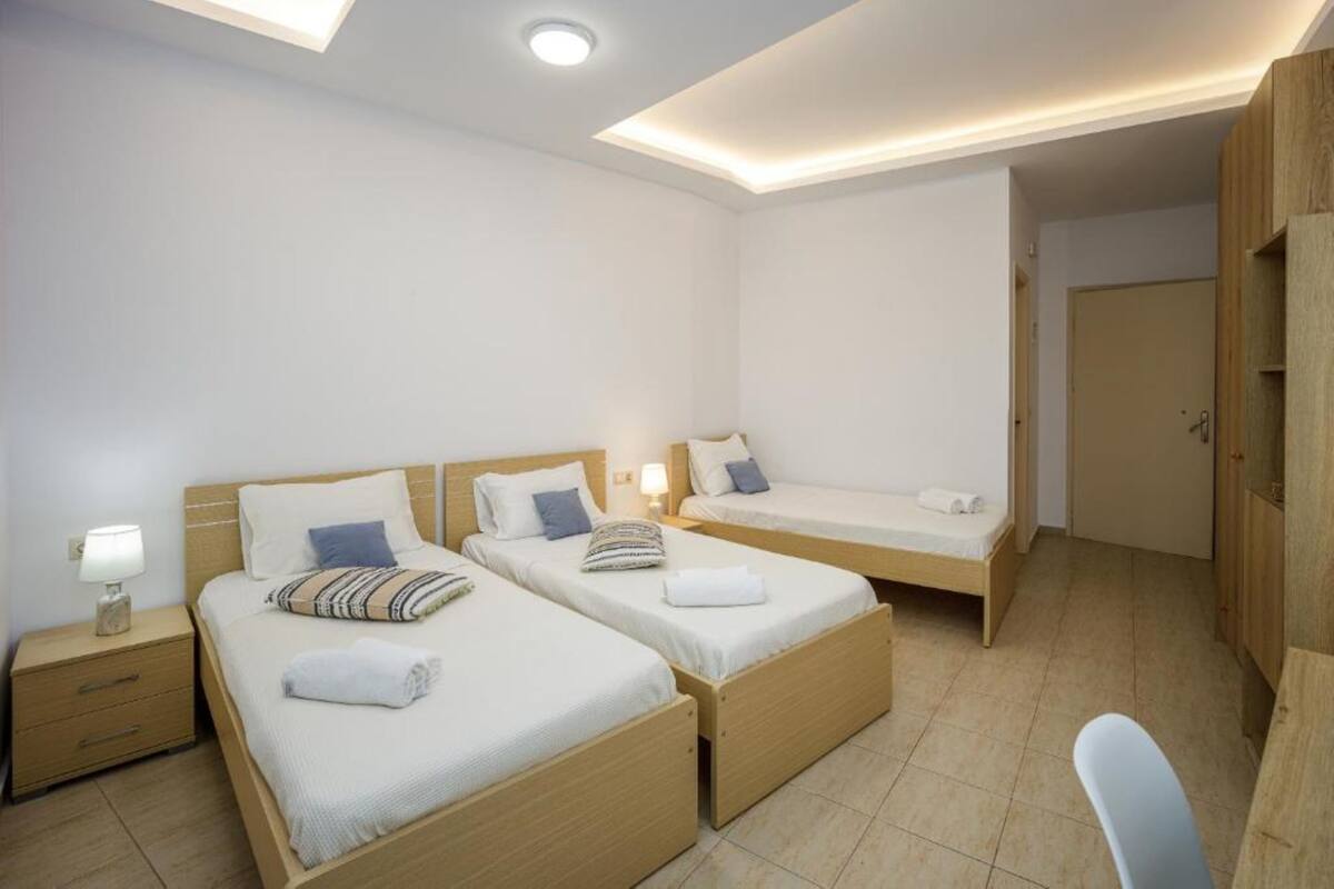 Een hotelkamer met twee enkele bedden, een bureau en een stoel.