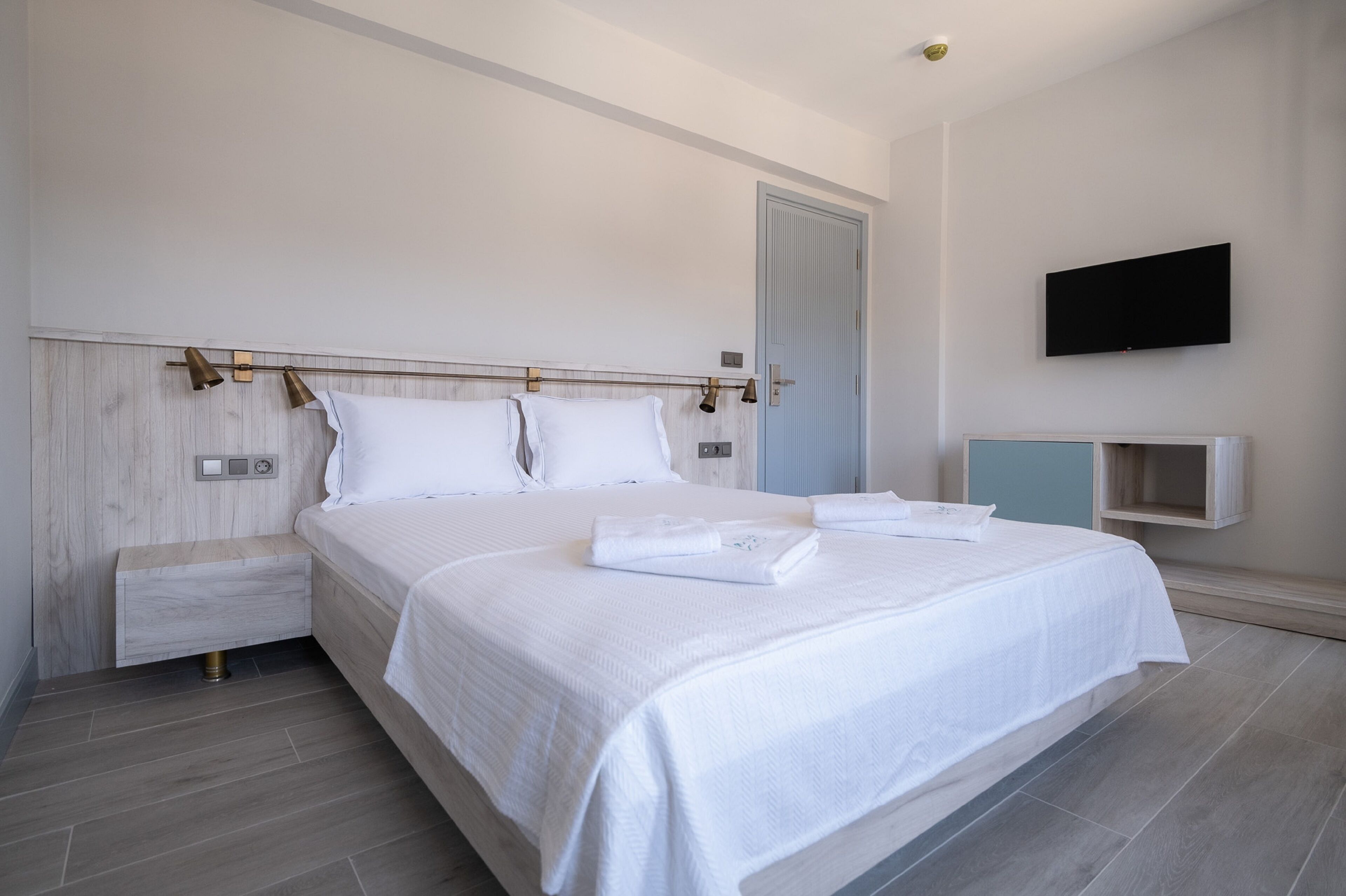 Un dormitorio moderno con una cama grande, mesitas de noche, un televisor de pantalla plana y un estante empotrado.