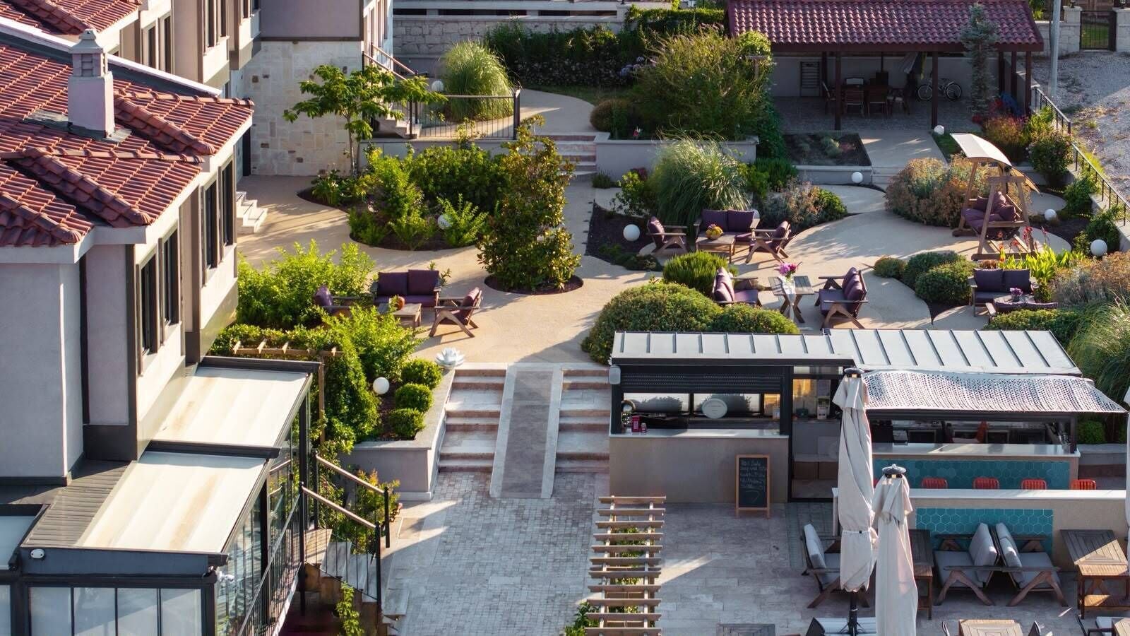 A rooftop terrace with outdoor seating, a pergola, and a small garden area.