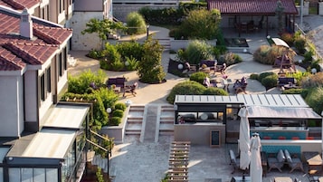 Una terraza en la azotea con mobiliario exterior, una pérgola y un pequeño jardín.