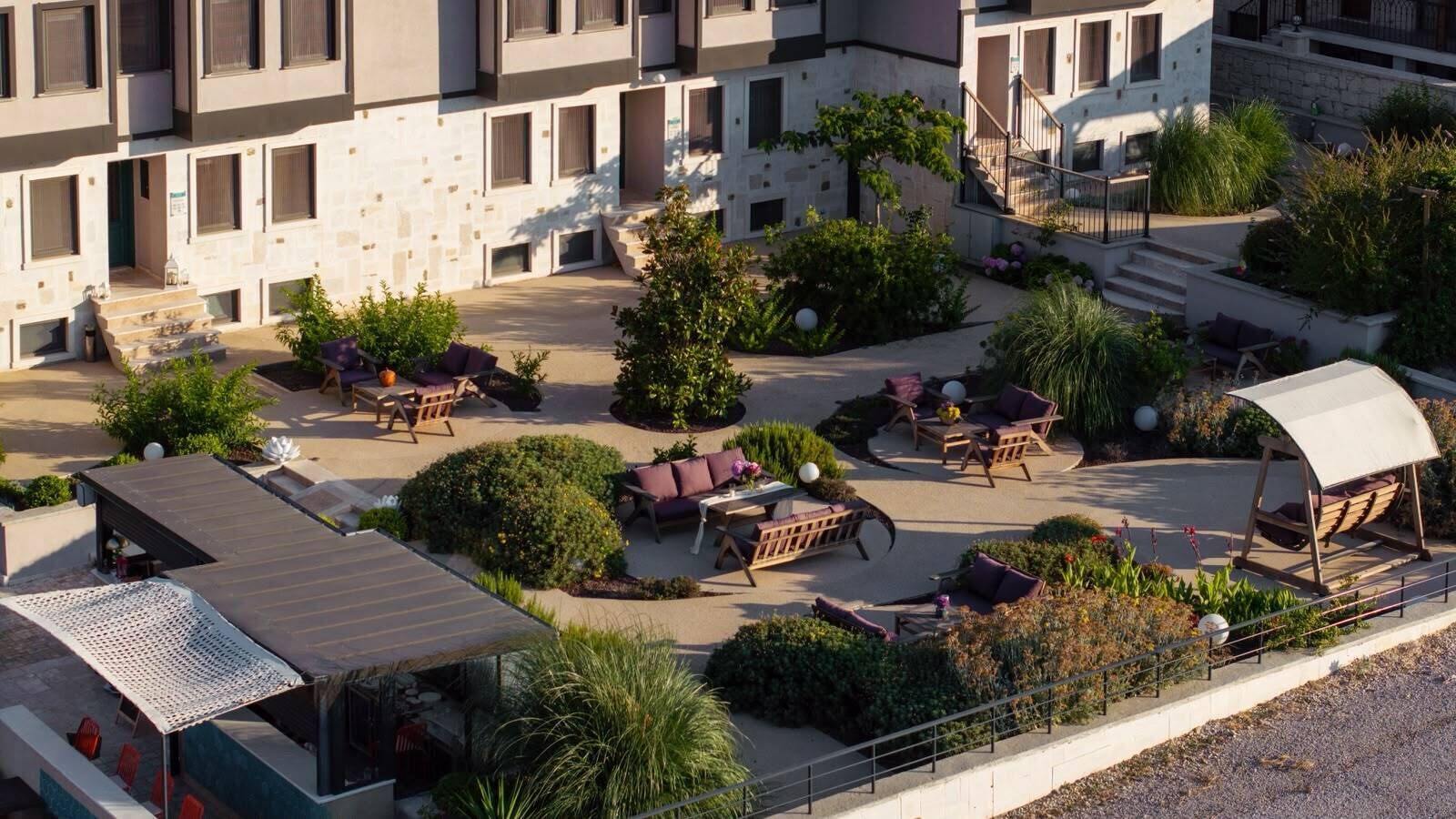 Un patio con mobiliario exterior, una zona cubierta y un edificio con varias ventanas.