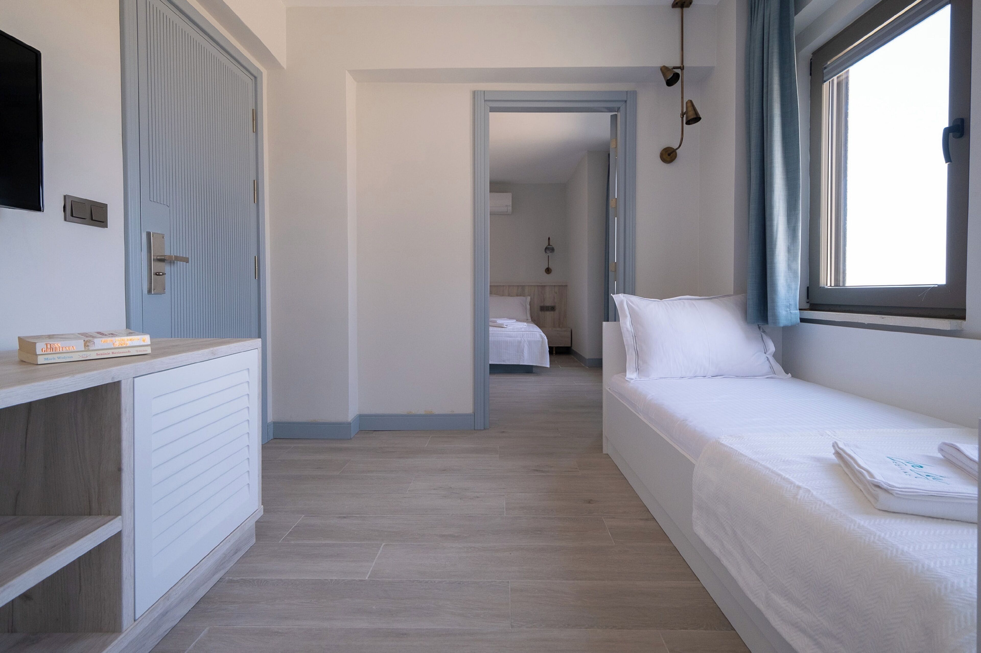 A hotel room with a bed, a bedside table, a wardrobe, and a window with curtains.