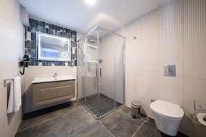 A modern bathroom with a glass-enclosed shower, a white toilet, and a vanity with a mirror.