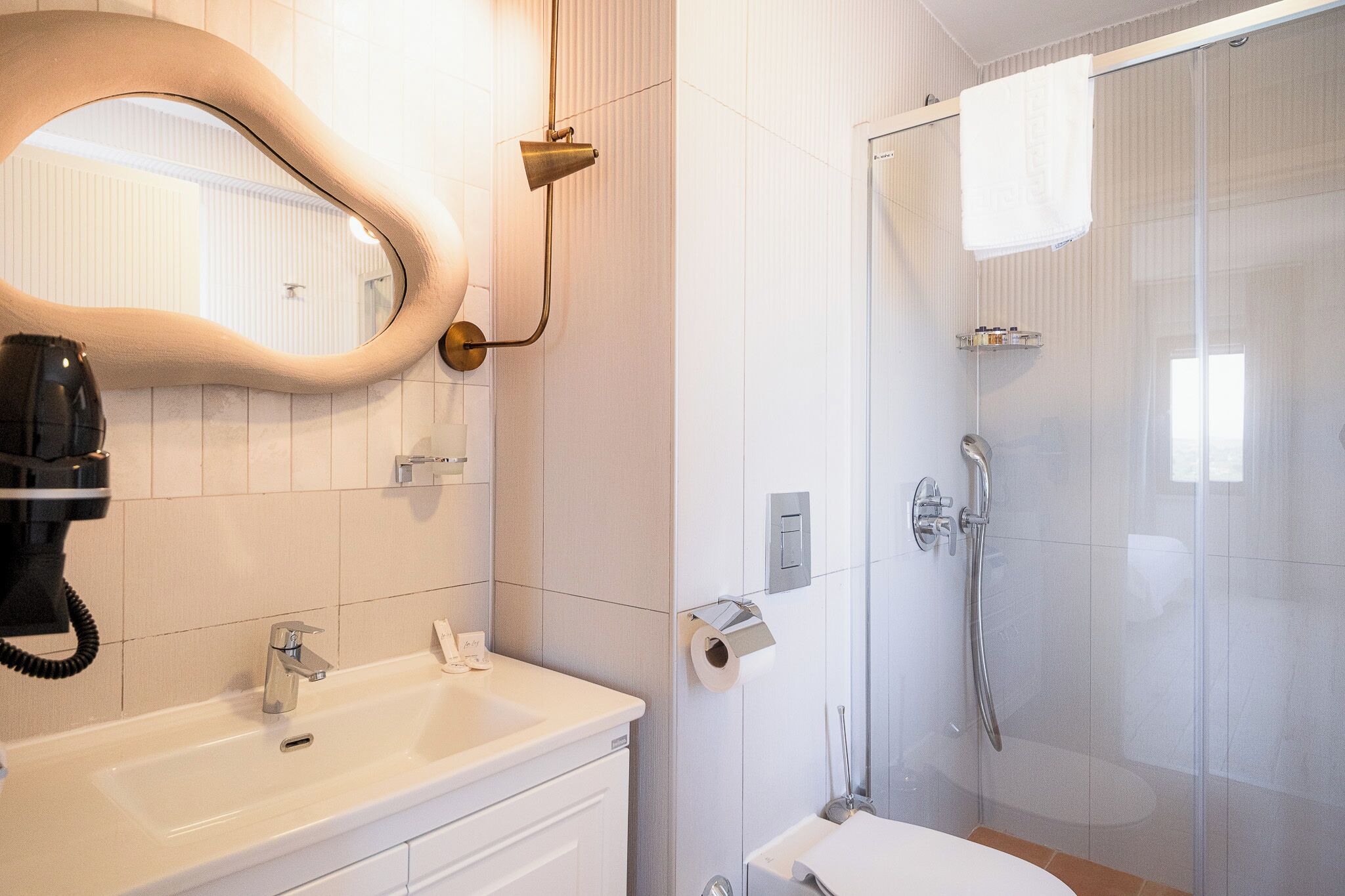 Un baño moderno con un espejo grande, un lavamanos, un inodoro y una ducha.