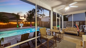 A covered outdoor area with a pool, seating, and a ceiling fan. - Beach Happy 315–Step-Free 3BR Near Beach–Pool+Cart (Panama City Beach)