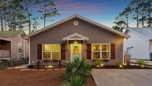 A single-story house with a gabled roof, a front porch with potted plants, and a number "315" sign above the door. - Beach Happy 315–Step-Free 3BR Near Beach–Pool+Cart (Panama City Beach)