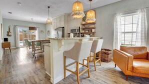 A spacious kitchen with a central island, wooden bar stools, and pendant lighting. - Beach Happy 315–Step-Free 3BR Near Beach–Pool+Cart (Panama City Beach)