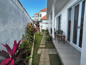 Stroll along the garden path to a serene patio area with a table and chairs, surrounded by lush greenery.
