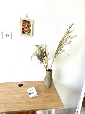 Simple, serene space with a wooden desk, framed artwork, and a vase with pampas grass.