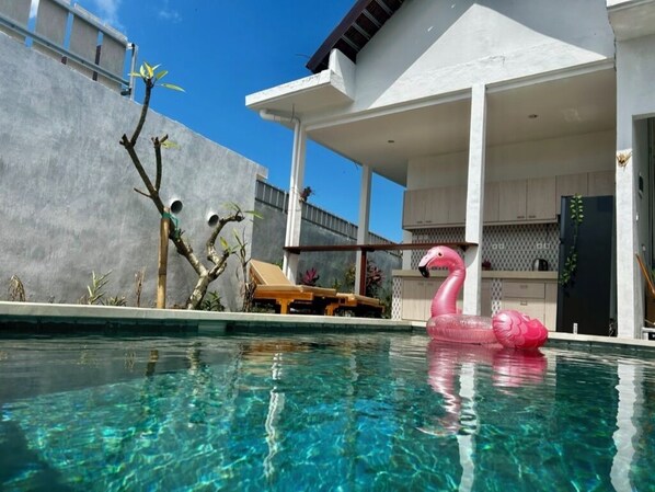 Relax by the pool in a serene outdoor space with a clear blue pool and adjacent patio area.