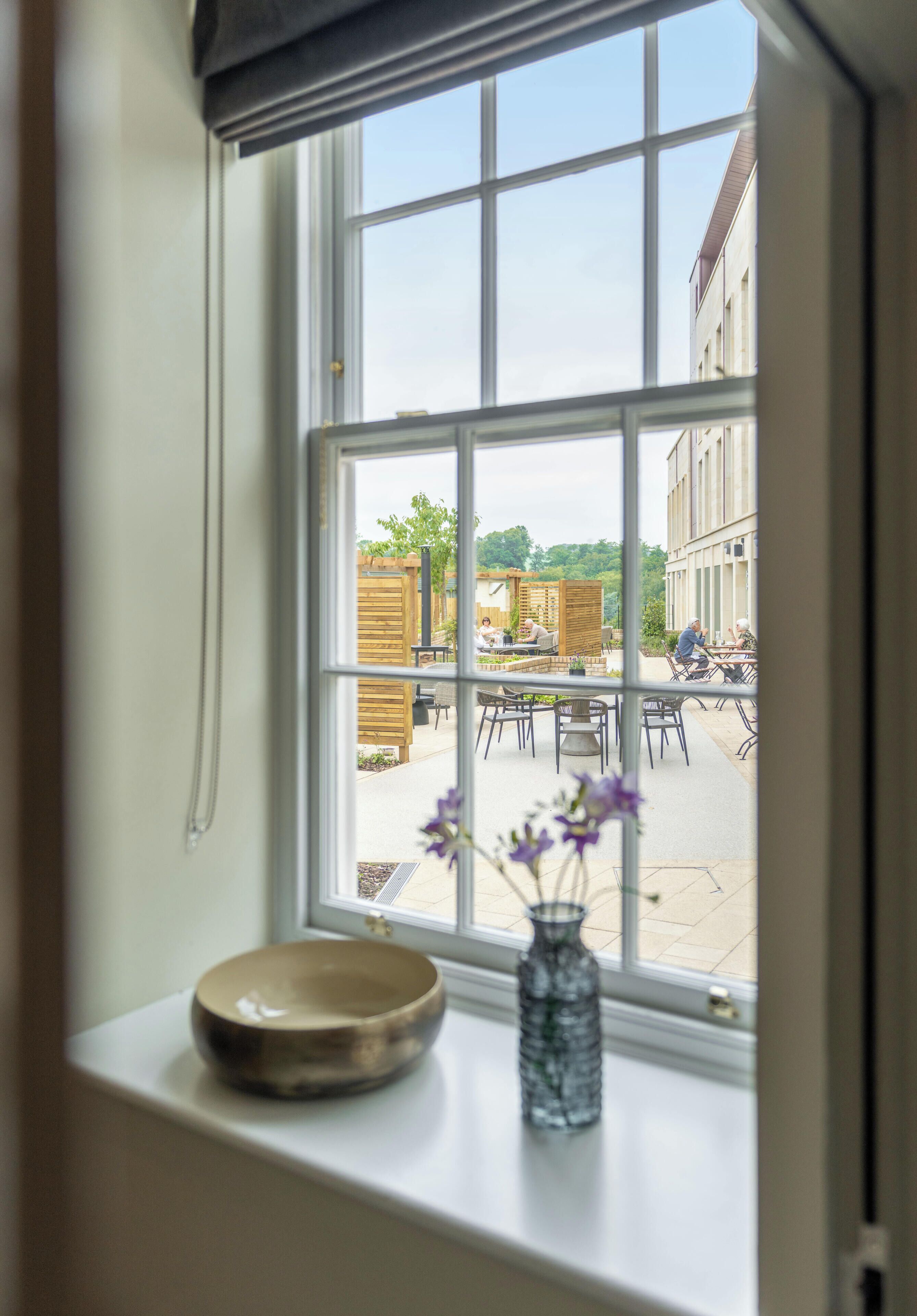 A window with a view of an outdoor patio area with tables and chairs.