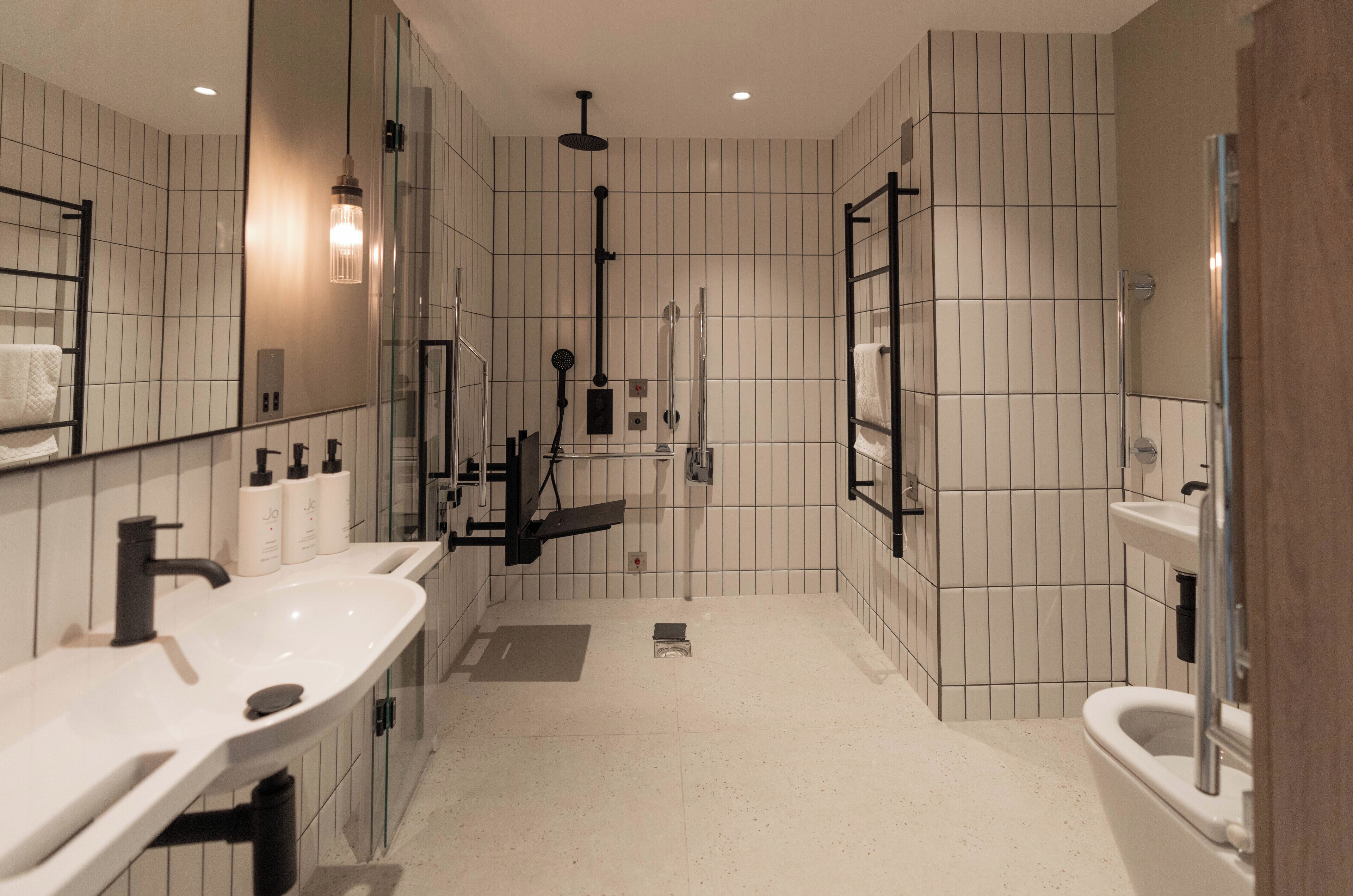 Une salle de bain moderne avec un grand miroir, deux lavabos, une douche et des toilettes.