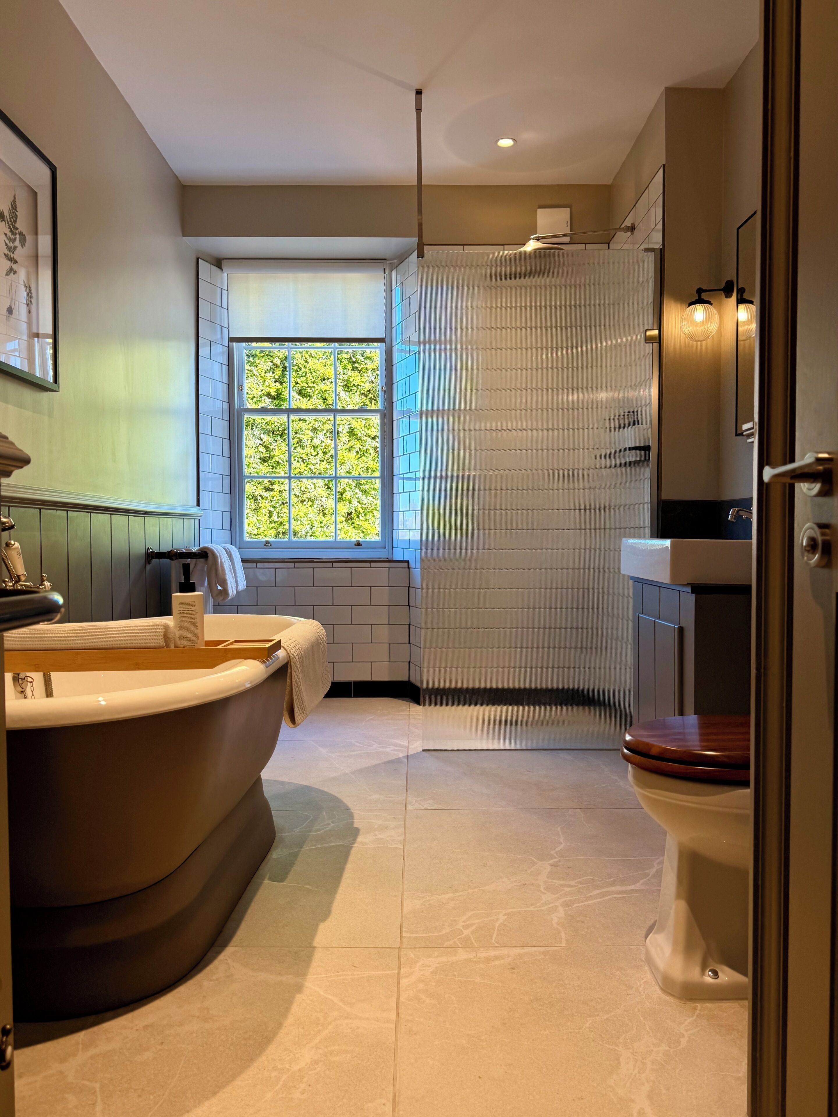 A modern bathroom with a freestanding bathtub, a toilet, and a window providing natural light.