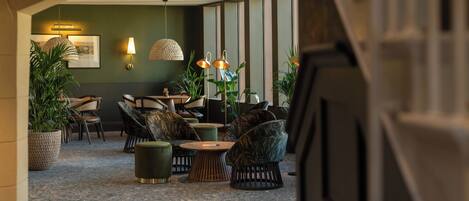 Un espacio lounge moderno con asientos, plantas e iluminación colgante.