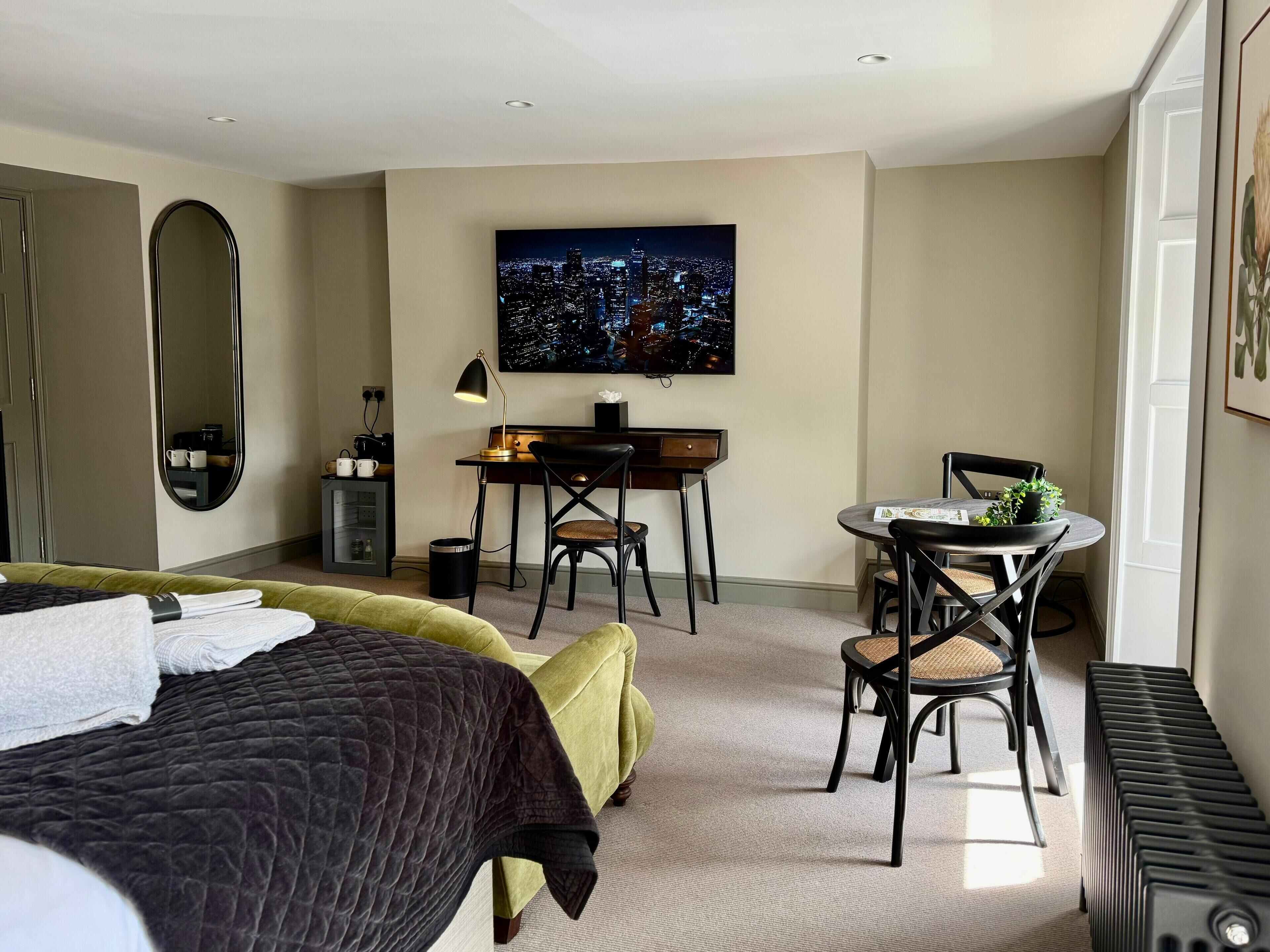 Una habitación de hotel moderna con una cama, un escritorio, una silla, un televisor y un radiador.