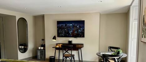 Una habitación de hotel moderna con una cama, un escritorio, una silla, un televisor y un radiador.