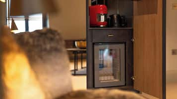 A compact kitchen with a refrigerator, a coffee maker, and a kettle.