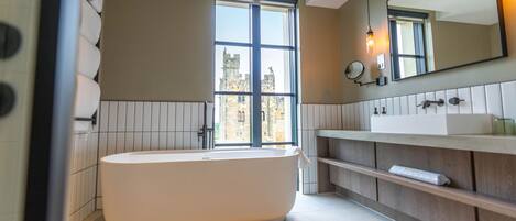 Un baño moderno con una bañera independiente, un espejo grande y una ventana que ofrece vistas a la ciudad.