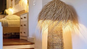 Un escalier menant à une chambre à coucher équipée d’un lit, d’une table de chevet et d’une lampe.