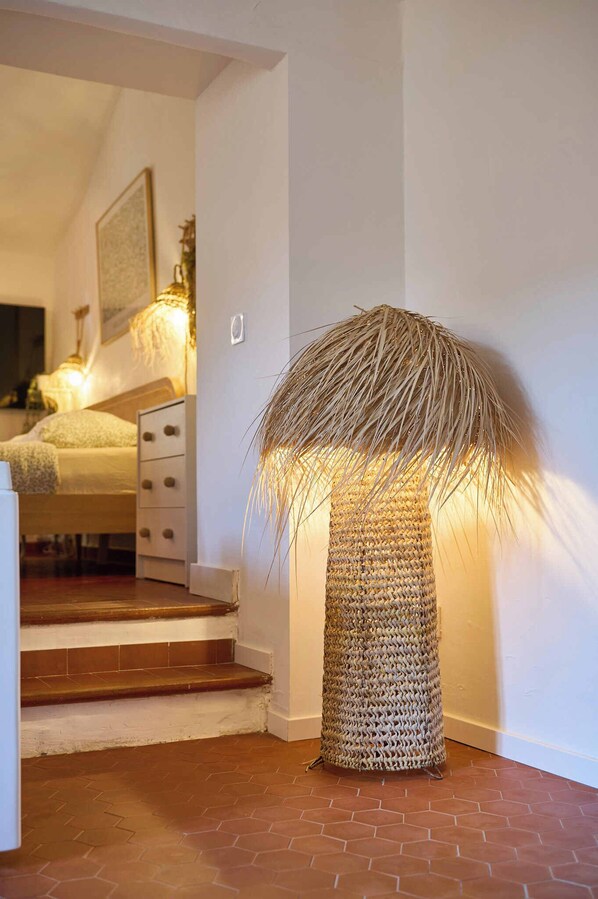 Eine Treppe führt zu einem Schlafzimmer mit einem Bett, einem Nachttisch und einer Lampe.