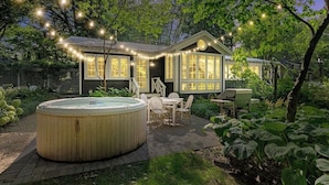 Une maison avec un jacuzzi, un espace salon extérieur et des guirlandes lumineuses.