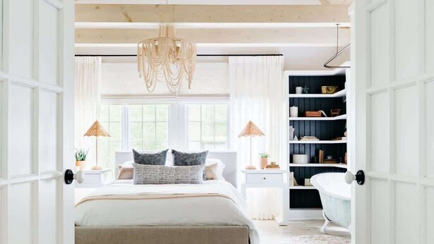 Une chambre à coucher avec un grand lit, un lustre, une bibliothèque et un tapis à motifs.