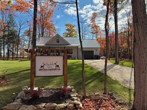 A sign for Stonchedge View, a building with a garage, surrounded by trees and a gravel driveway. - Modern Egg Harbor Home | Dog-Friendly + Fire Pit (Egg Harbor)
