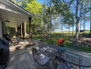 An outdoor patio with a covered seating area, a table with chairs, and a potted plant. - Modern Egg Harbor Home | Dog-Friendly + Fire Pit (Egg Harbor)
