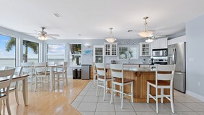 Una cocina moderna con armarios blancos, una isla central con taburetes y vistas al agua.