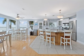 A modern kitchen with white cabinetry, a central island with bar stools, and a view of the water.