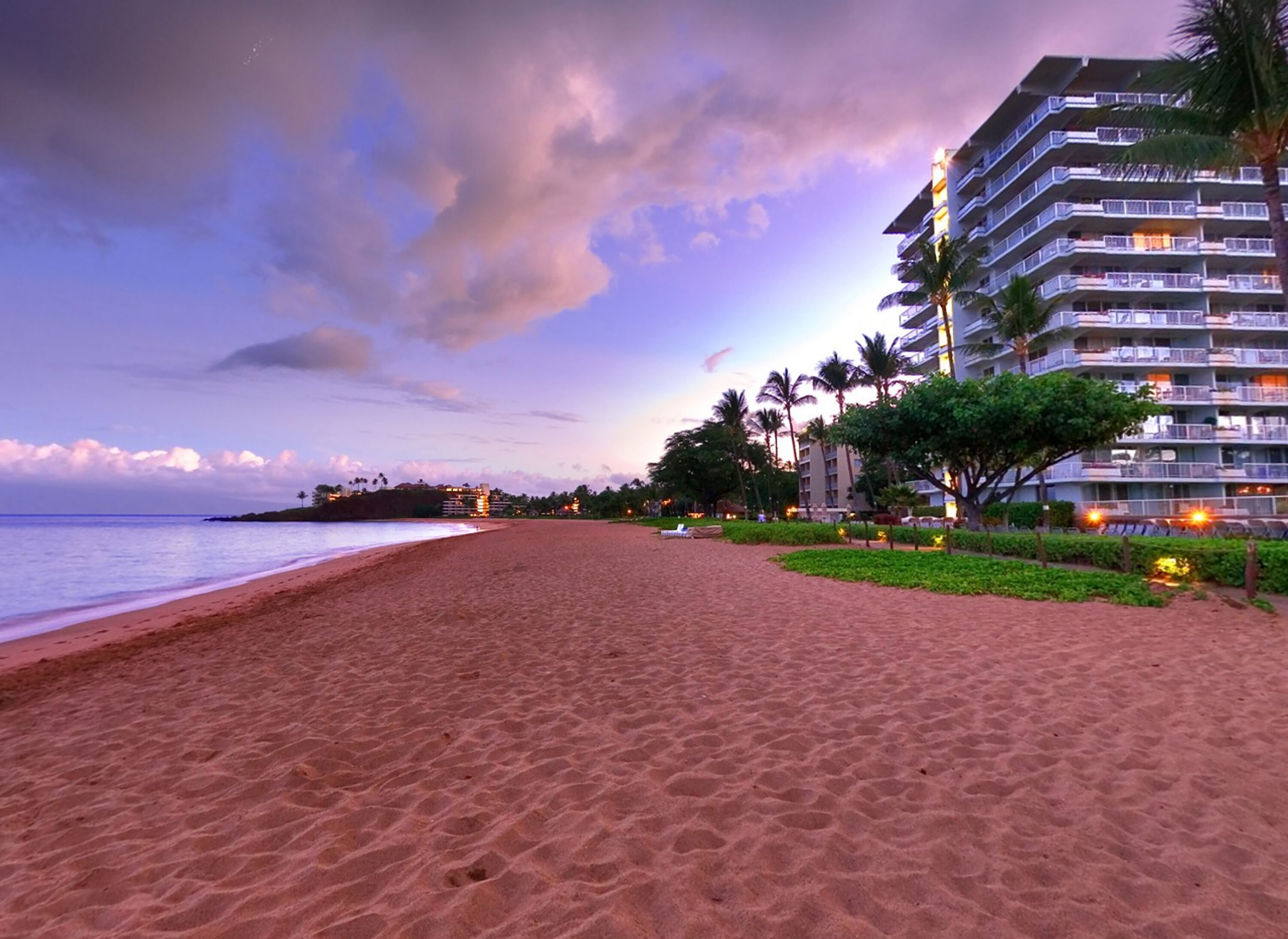 Ein Strand mit einem Hotel im Hintergrund.