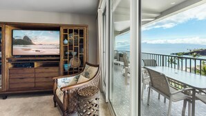 Un balcón con vistas al océano y un área de comedor con mesa y sillas.