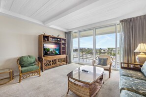 Relax in a spacious living room with a high ceiling, comfortable seating area, and sliding glass door leading to a balcony.