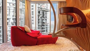 Uma sala de estar moderna com um sofá vermelho, janelas amplas e uma cadeira de madeira singular.