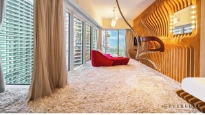 Quarto de hotel moderno com uma janela grande, um sofá vermelho e um design de parede de madeira exclusivo.