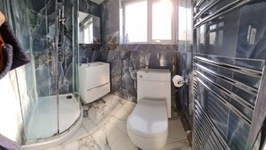 A bathroom with a glass-enclosed shower, a toilet, and a sink.