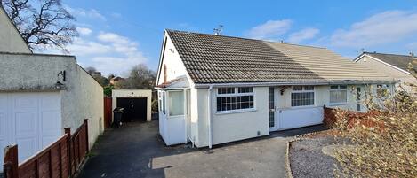 A residential property with a garage, a covered driveway, and a white exterior.