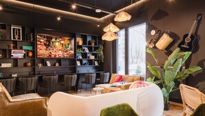 A modern living area with a sofa, chairs, a dining table, and a bookshelf. - Rioca Stuttgart Posto 6 (Stuttgart)