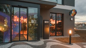 A modern building with large glass windows, a digital display, and a colorful sign. - Rioca Stuttgart Posto 6 (Stuttgart)
