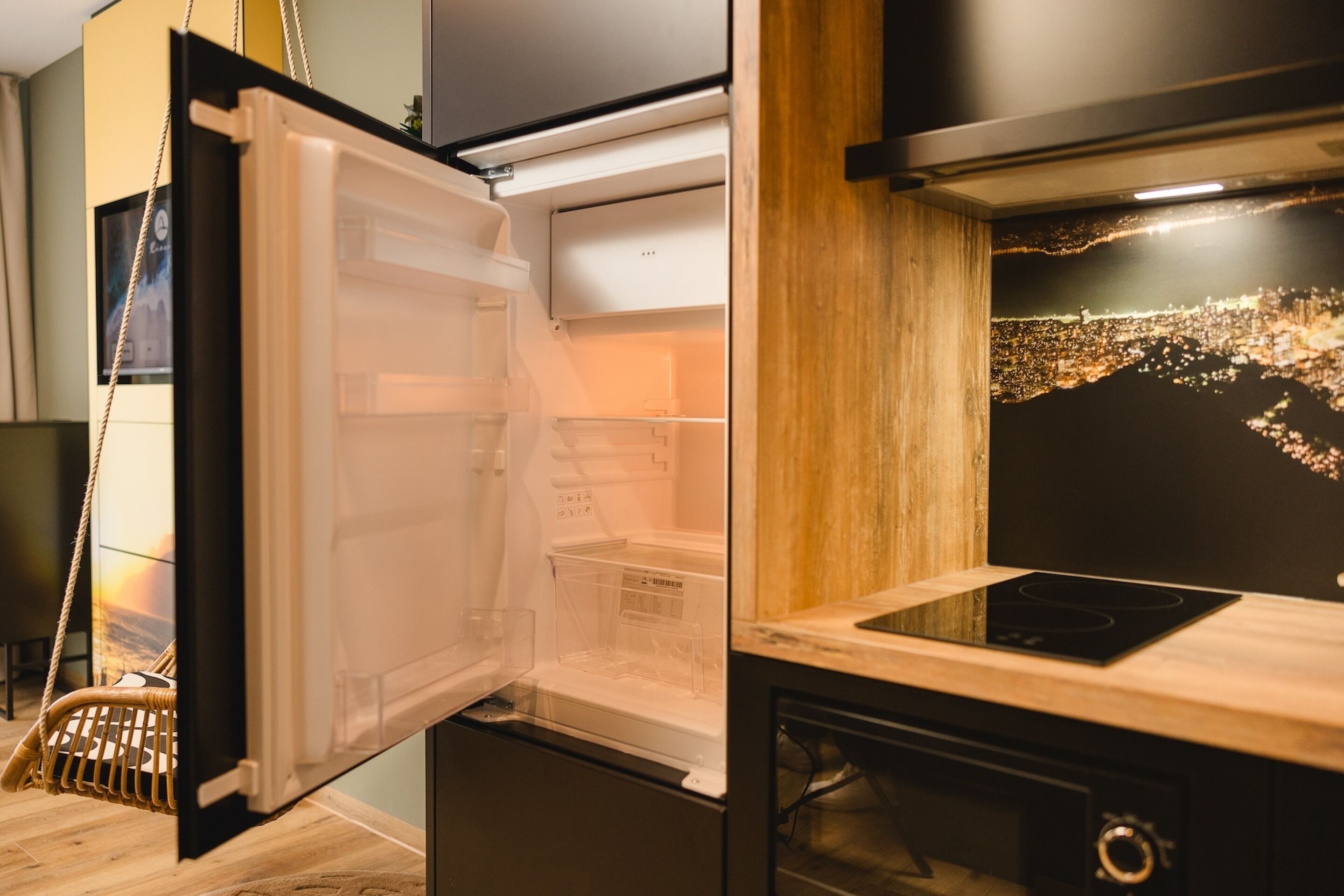 A modern kitchen with a built-in refrigerator, a wooden countertop, and a cityscape mural on the wall.