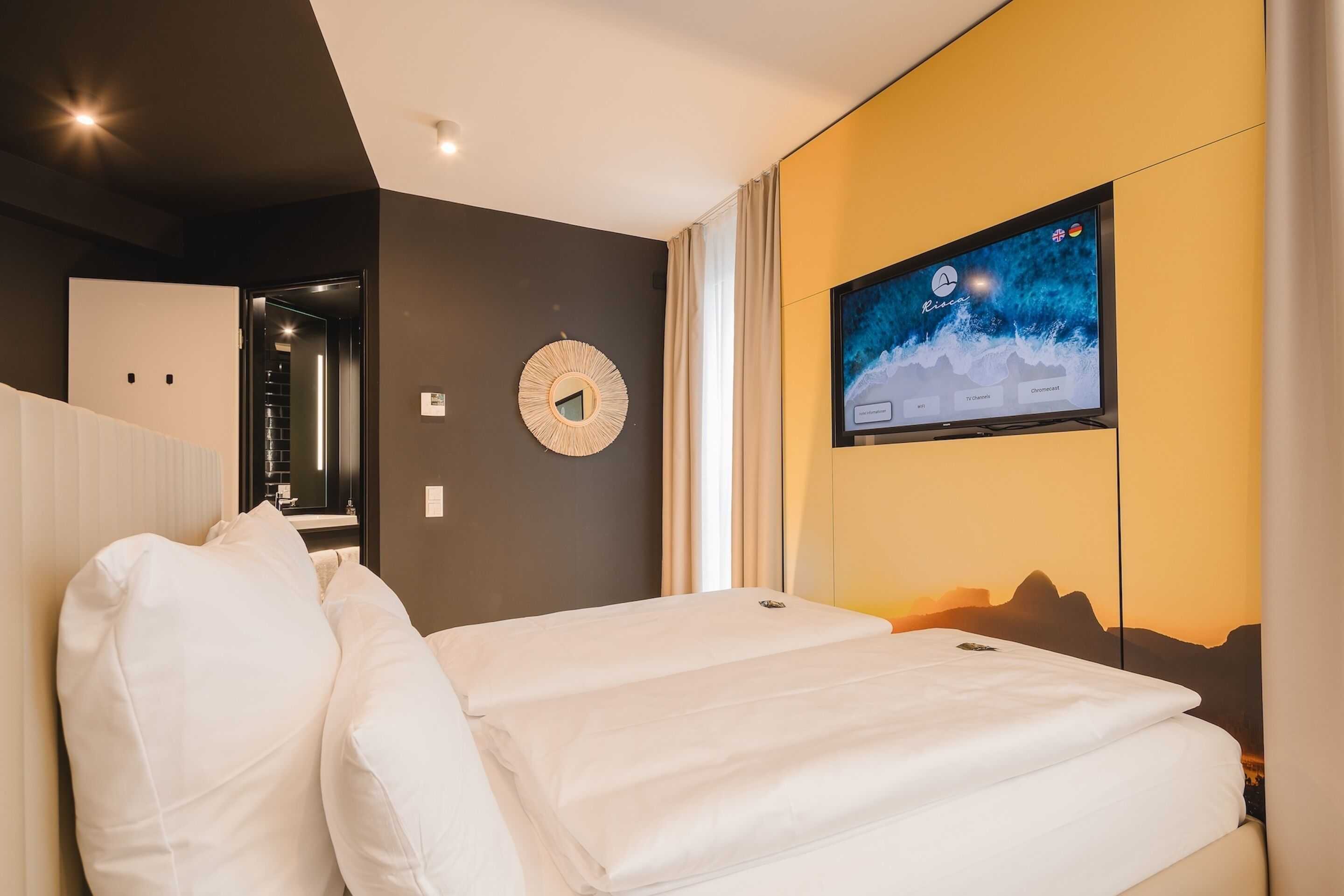 Ett modernt hotellrum med en säng, en tv som är monterad på väggen och utsikt över bergen.