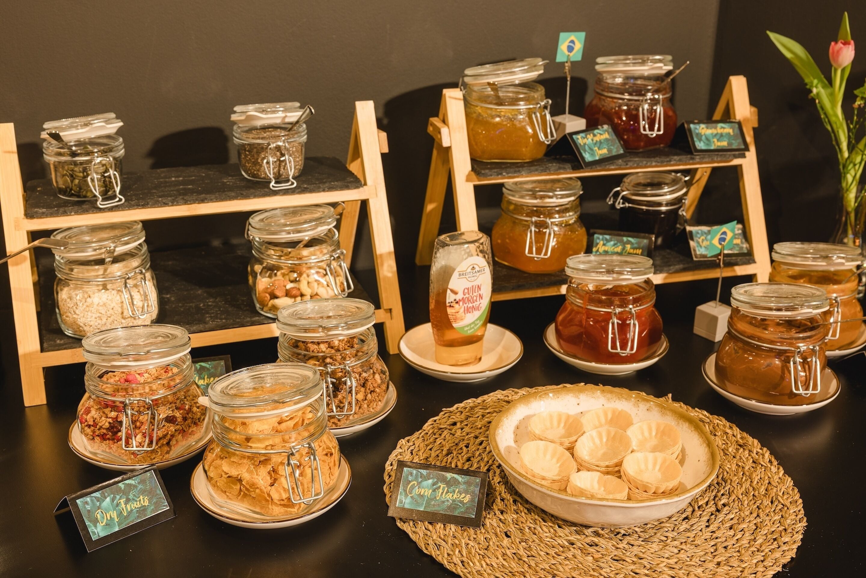 A display of various food items including jars of preserves, dry fruits, and cookies on a table.