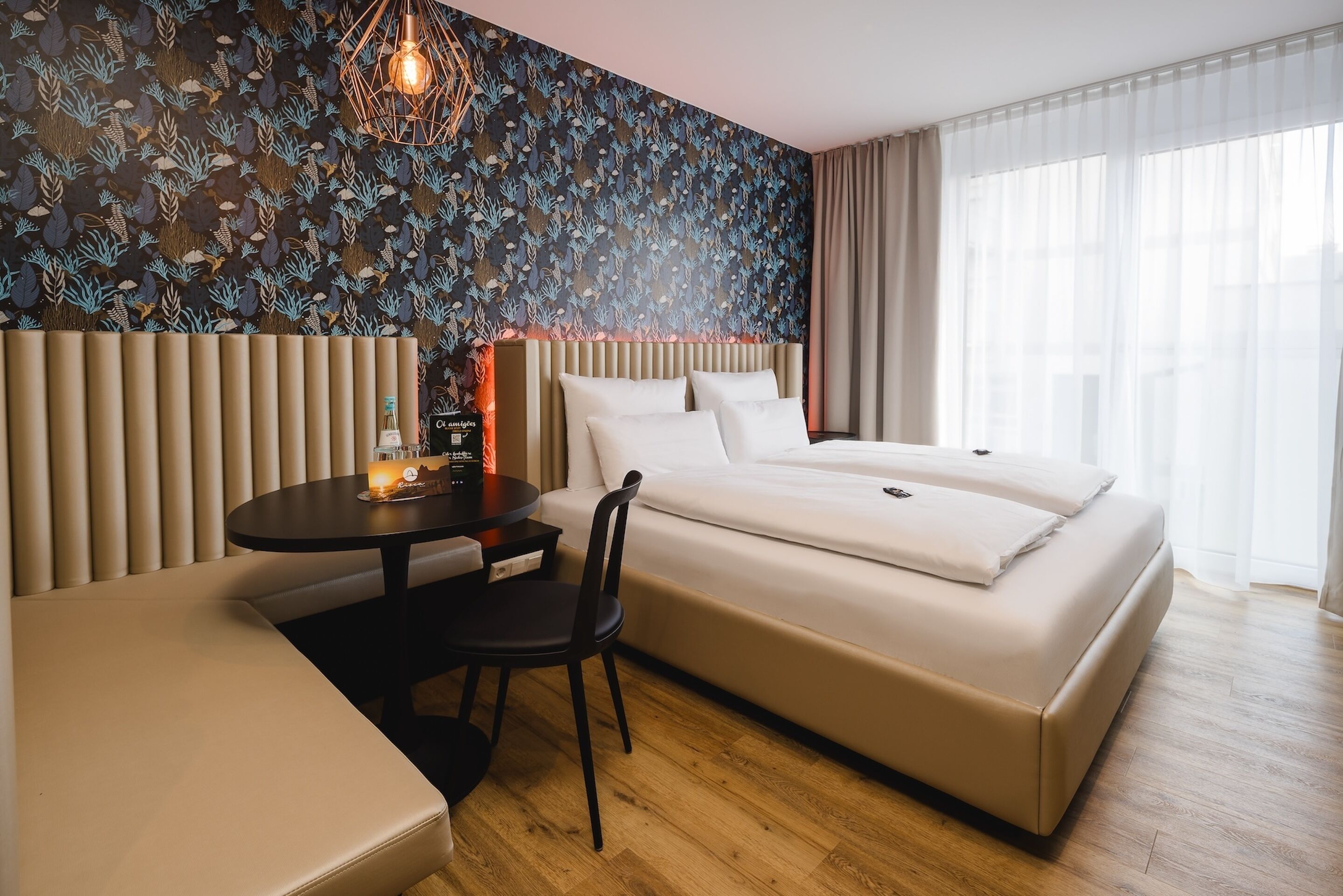 Una habitación de hotel moderna con una cama grande, una pequeña mesa redonda con una silla y un área de descanso.
