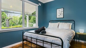 A bedroom with a bed, a window, and a framed picture on the wall.