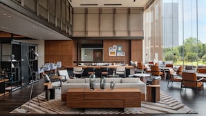 A spacious lobby with a central seating area, a kitchen in the background, and large windows offering a view of the outdoors. - Sheraton Taizhou (Taizhou)