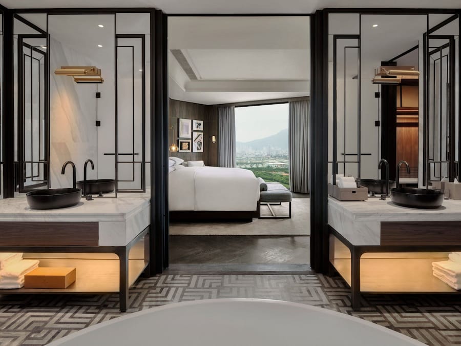 Camera d'hotel moderna con un letto grande, due bagni e vista sulla città.