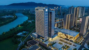 A Sheraton hotel with a modern design, surrounded by a river and mountains in the background. - Sheraton Taizhou (Taizhou)